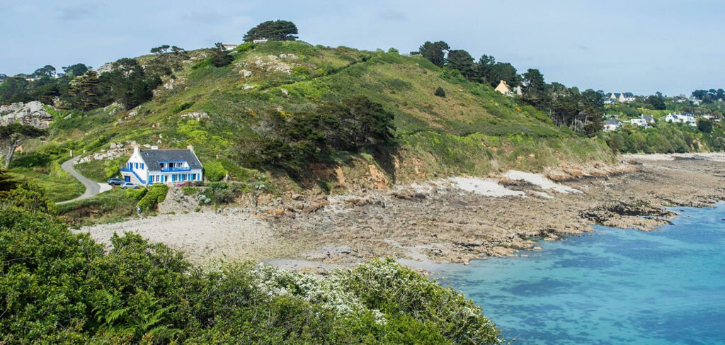 plage de galets et maison blanche aux volets bleus